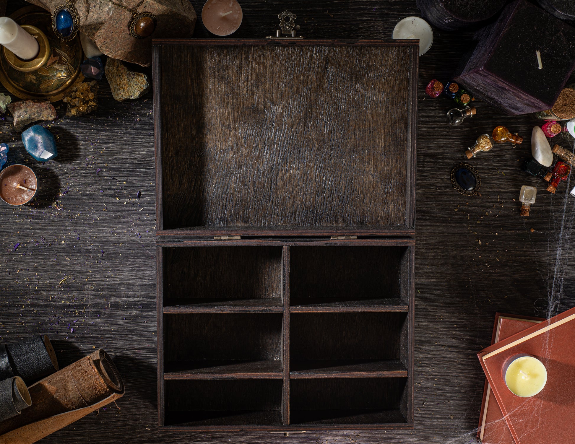 a wooden box with six compartments, surrounded by various objects such as candles, books, and other knick-knacks on a dark wooden surface.