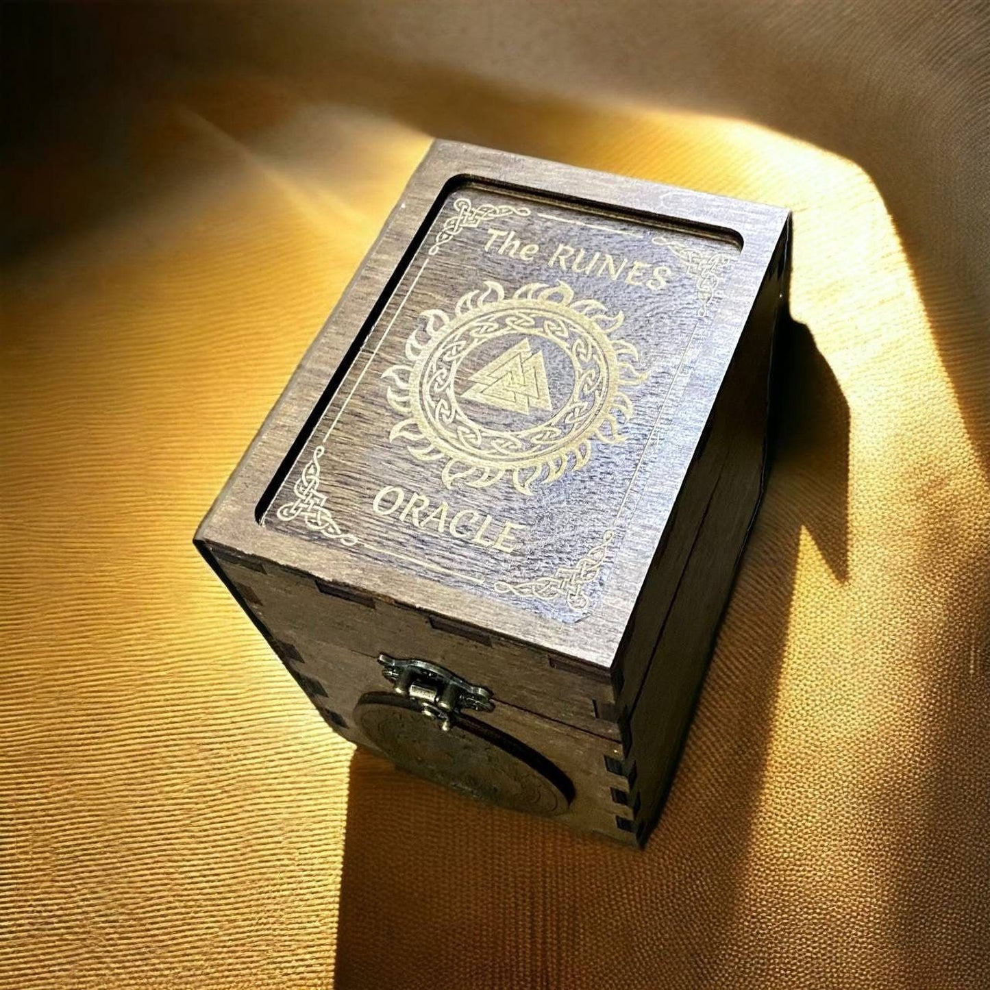 A wooden box with the text "The RUNES Oracle" on it, placed on a textured surface with a warm, golden glow.