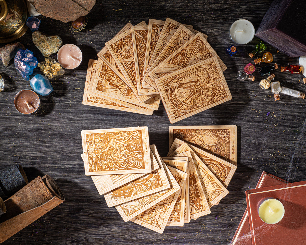 a collection of wooden tarot cards arranged on a dark wooden surface, along with various other objects such as candles, gemstones, and books.
