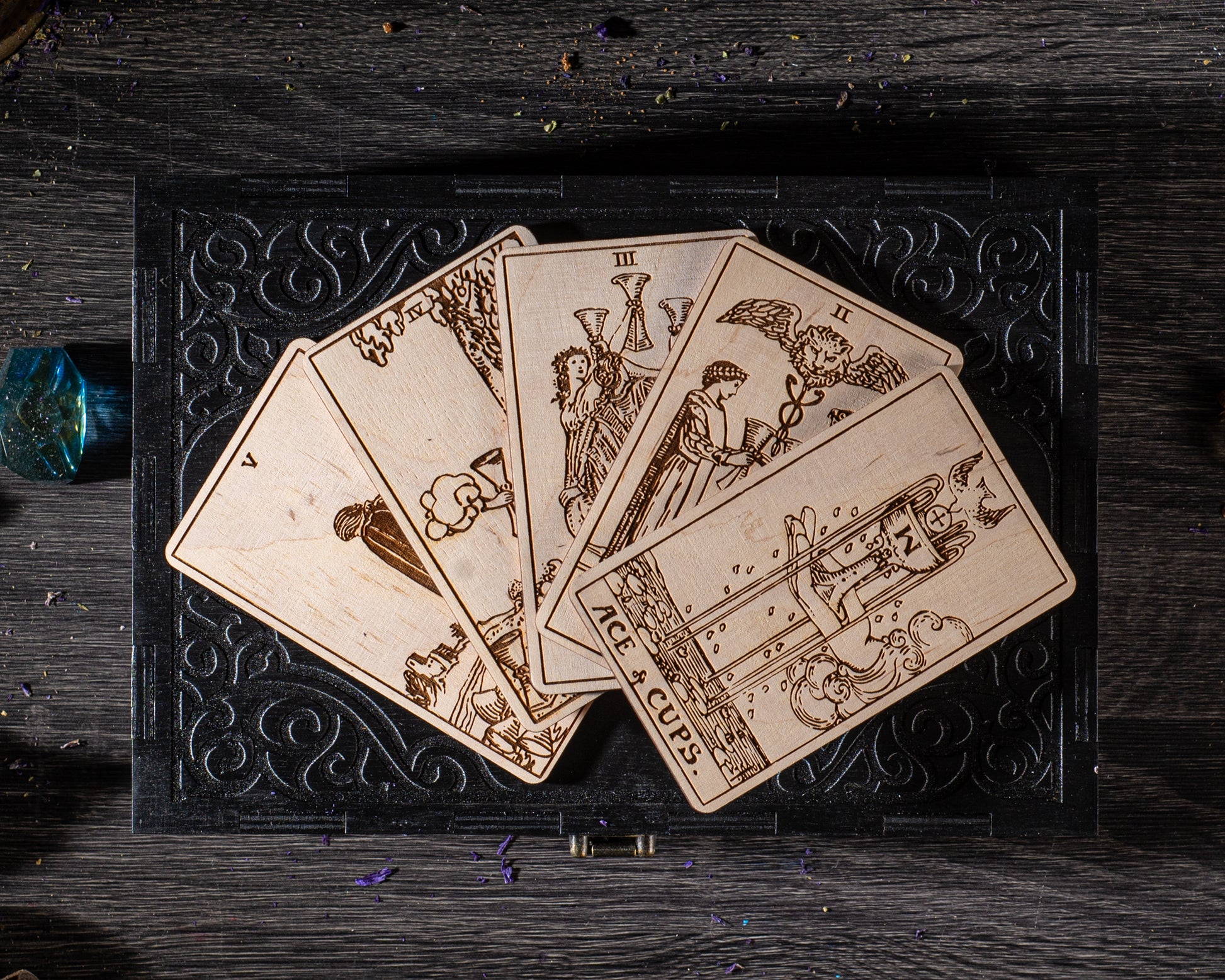 A collection of wooden tarot cards is displayed on a black surface, with intricate designs and illustrations.