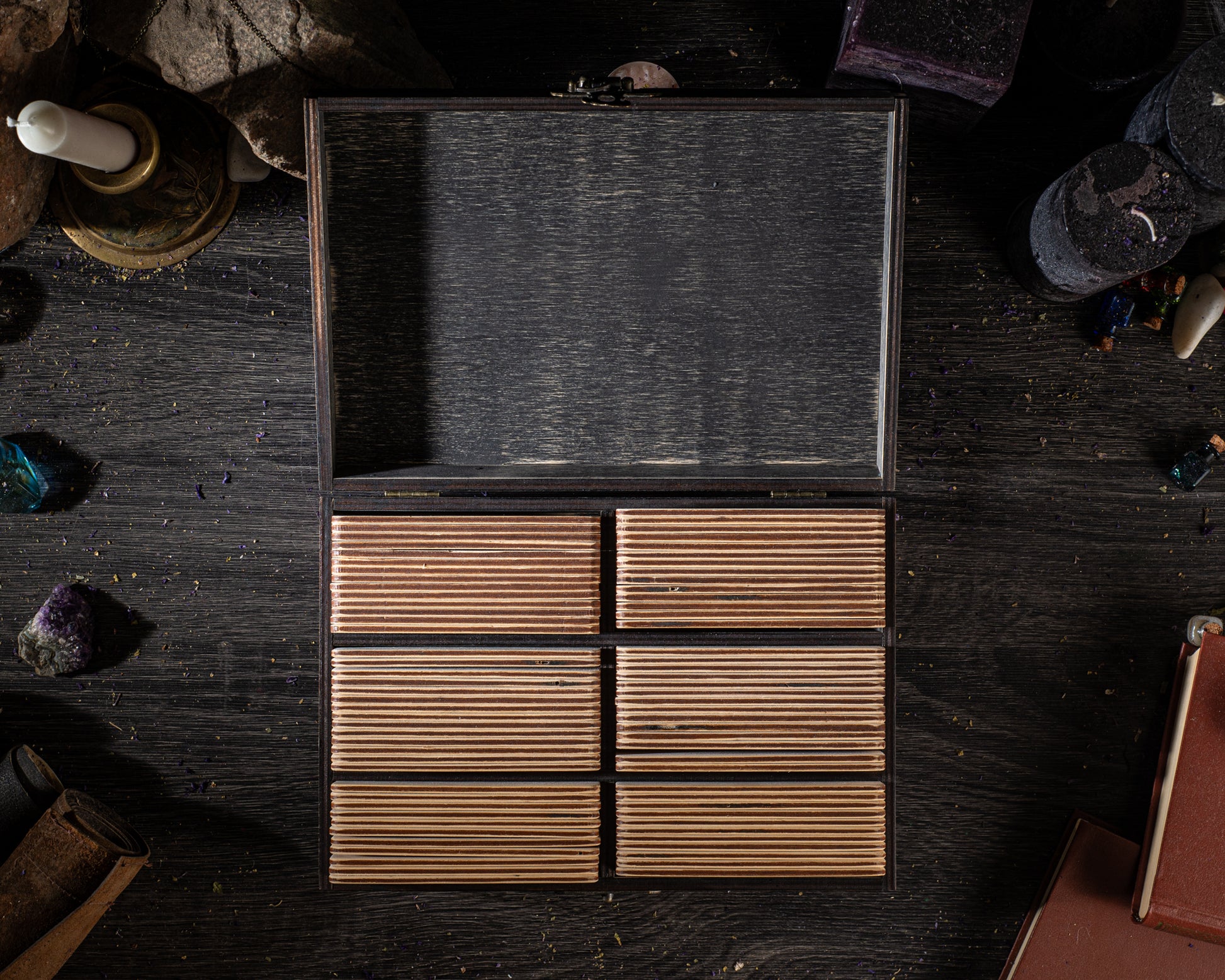 a wooden box with six compartments, placed on a dark wooden surface. The box appears to be empty, with no visible contents.