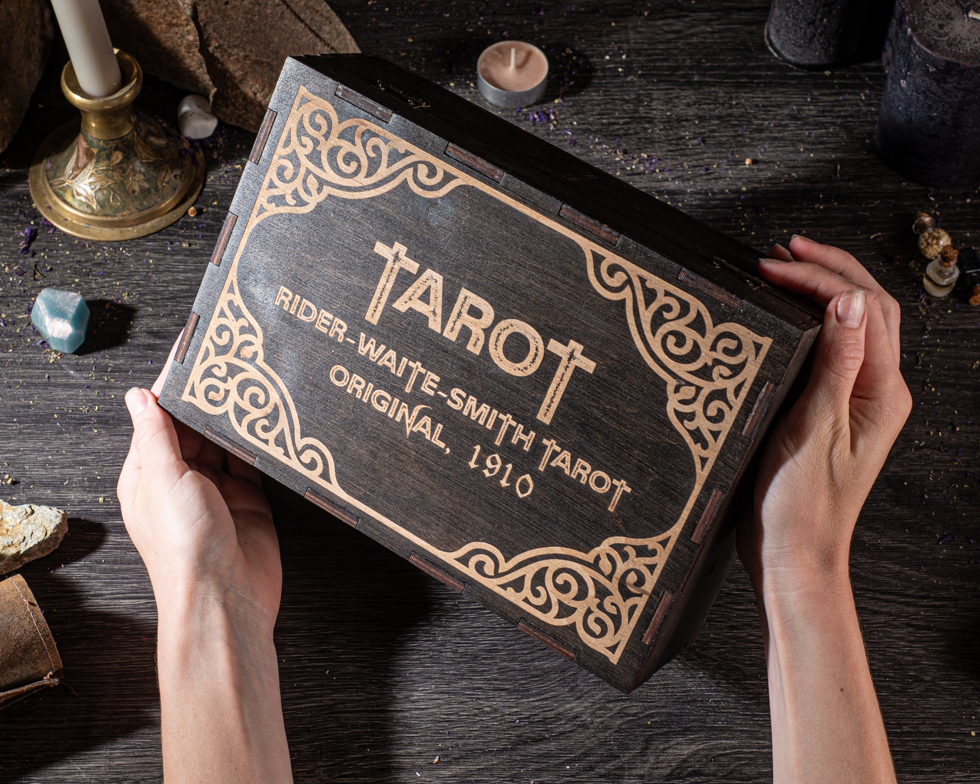 A person's hands holding a wooden box with the name "RIDER-WAITE-SMITH TAROT" printed on it, along with the year "1910".
