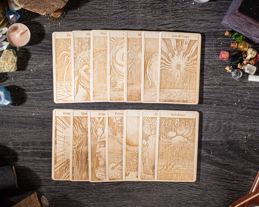 A collection of wooden tarot cards with intricate designs and illustrations, arranged on a dark wooden surface.