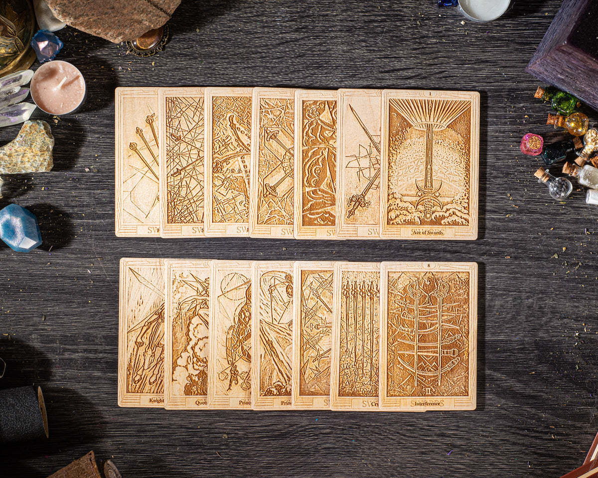 A collection of wooden tarot cards arranged on a dark wooden surface, with various intricate designs and illustrations.
