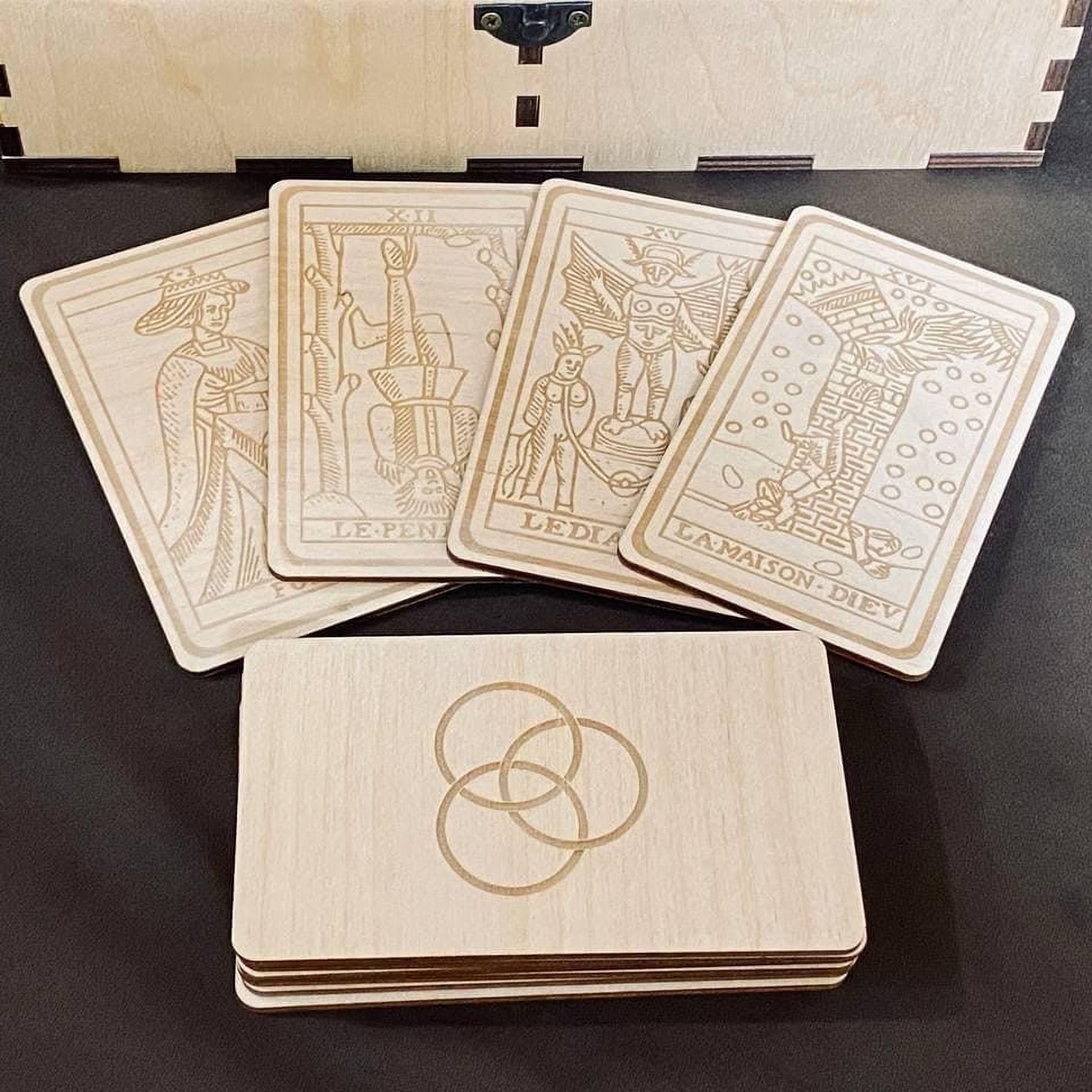 A set of wooden tarot cards and a wooden box with the same design, all featuring intricate engraved illustrations.