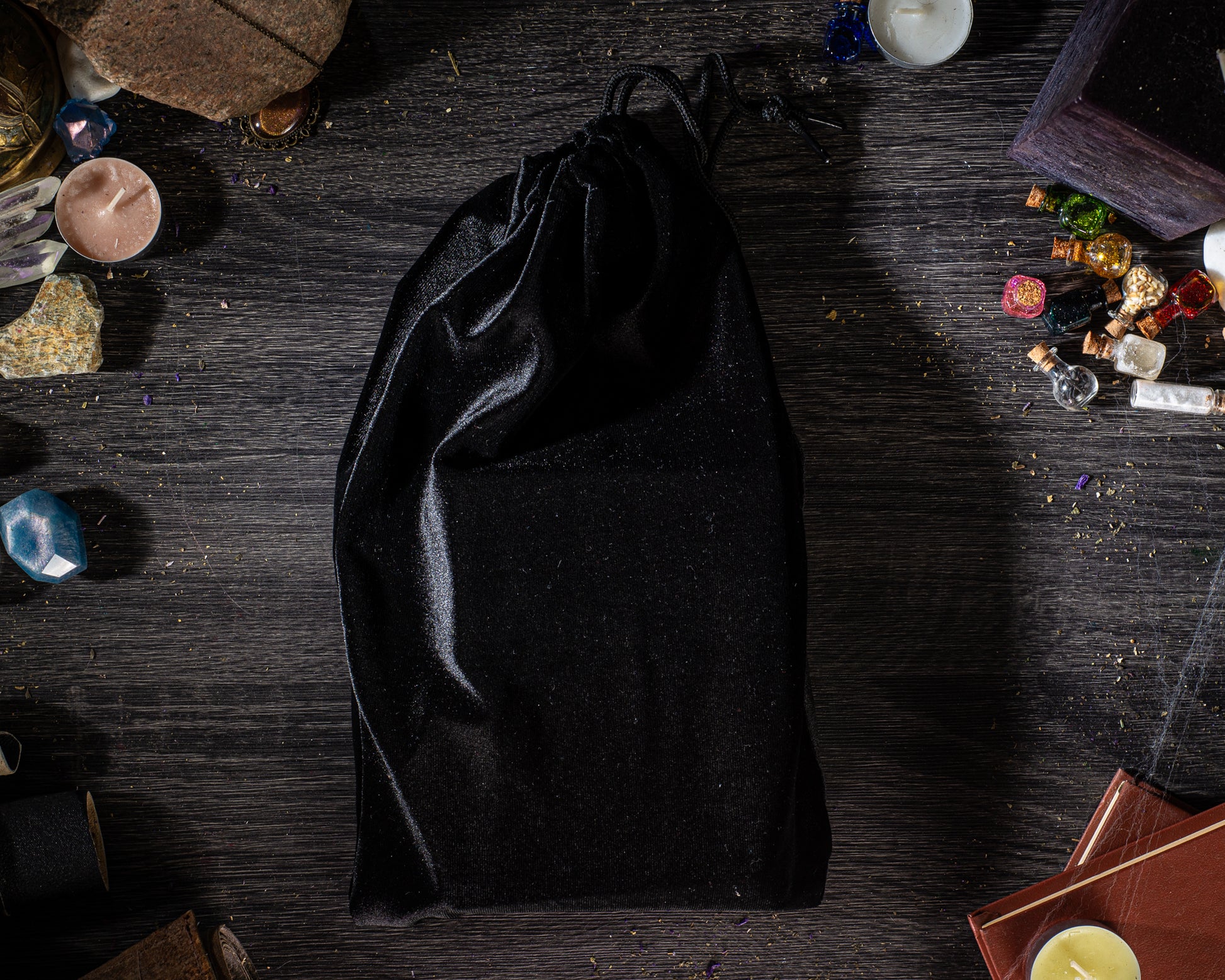 Black drawstring bag on a dark wooden surface with crystals and candles.