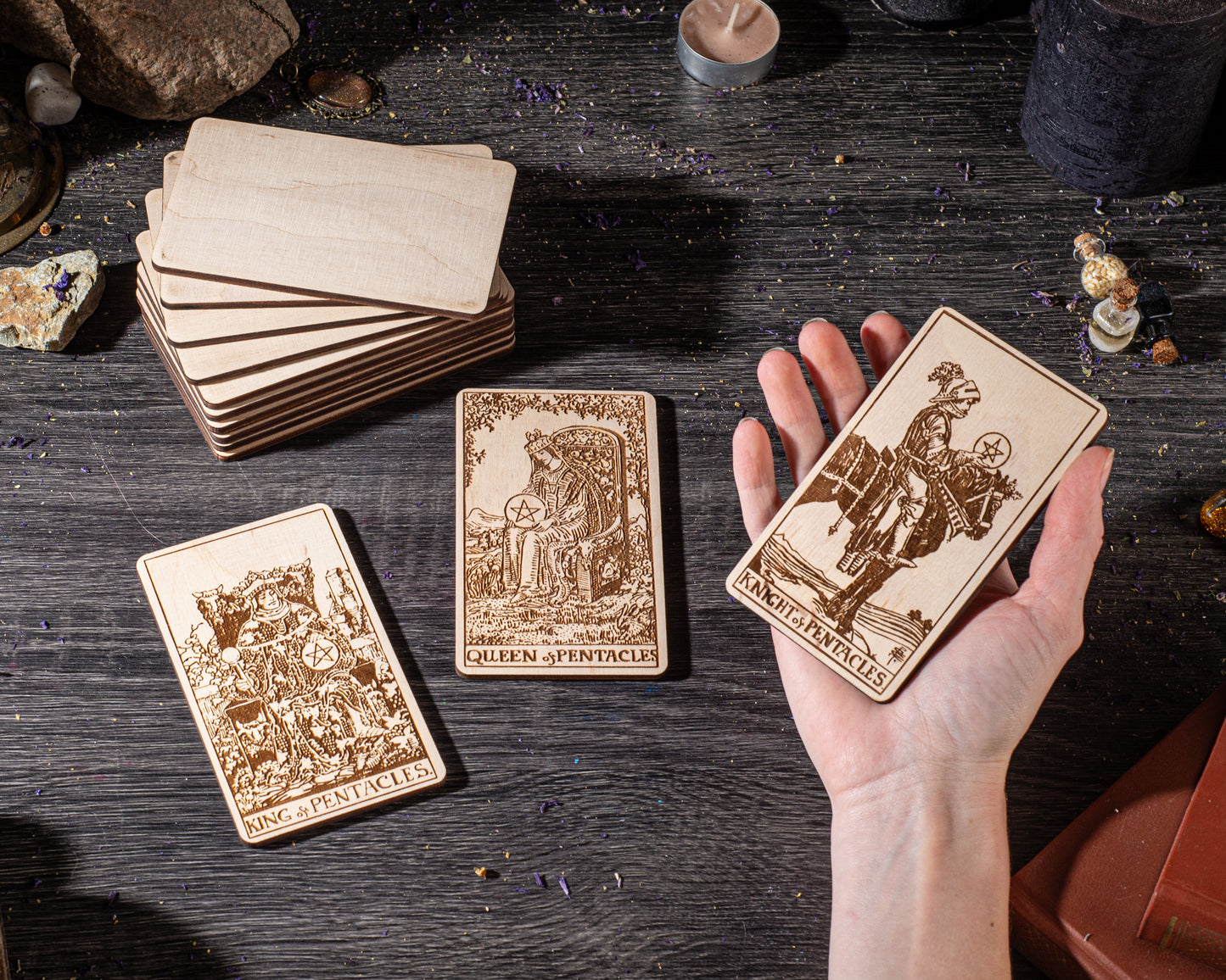a hand holding three wooden tarot cards, with a stack of additional cards visible in the background.