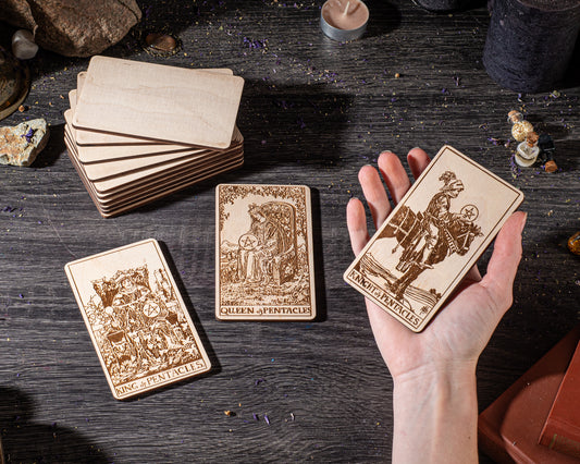 a hand holding three wooden tarot cards, with a stack of additional cards visible in the background.