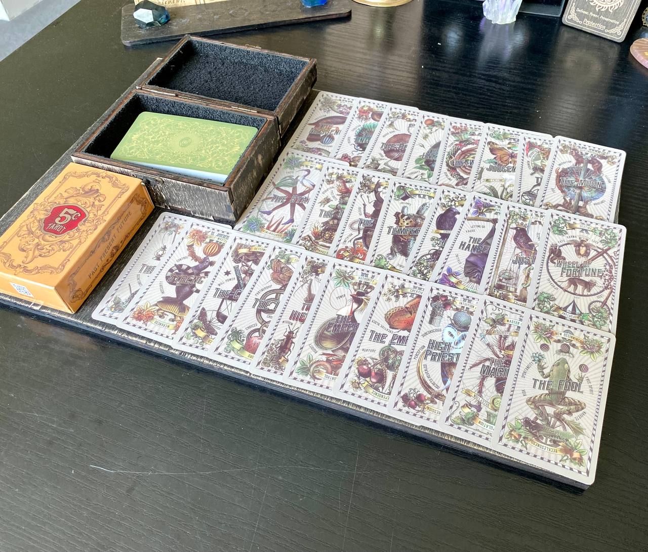 a collection of tarot cards and a box, arranged on a wooden surface.