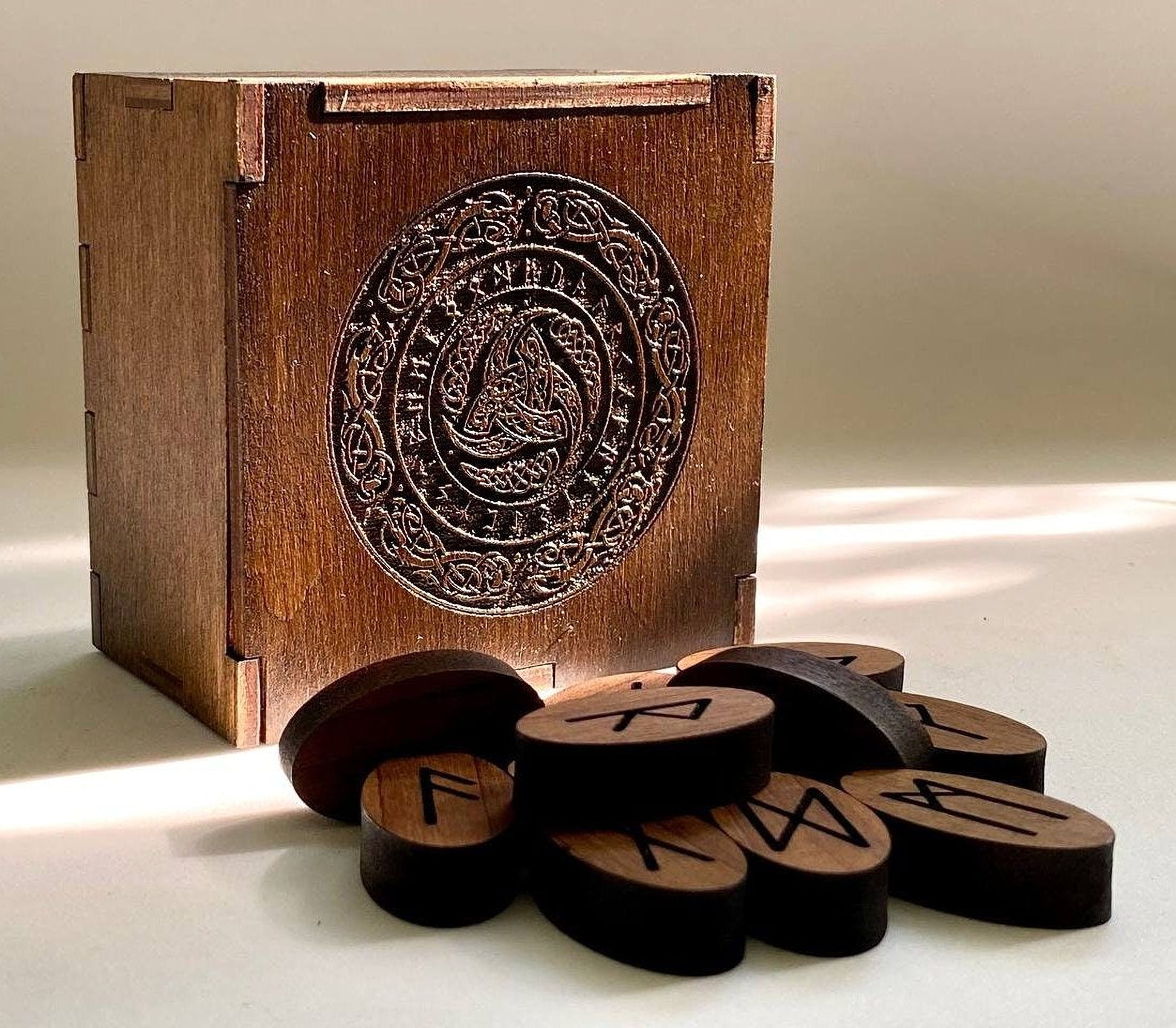 a wooden box with a carved design on the front, and there are several wooden pieces with symbols on them, including what appear to be the letters "V" and "W".