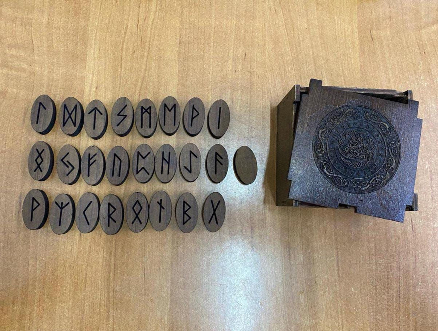 a collection of wooden objects, including a wooden box with a carved design and a row of wooden blocks with various symbols and letters carved into them.