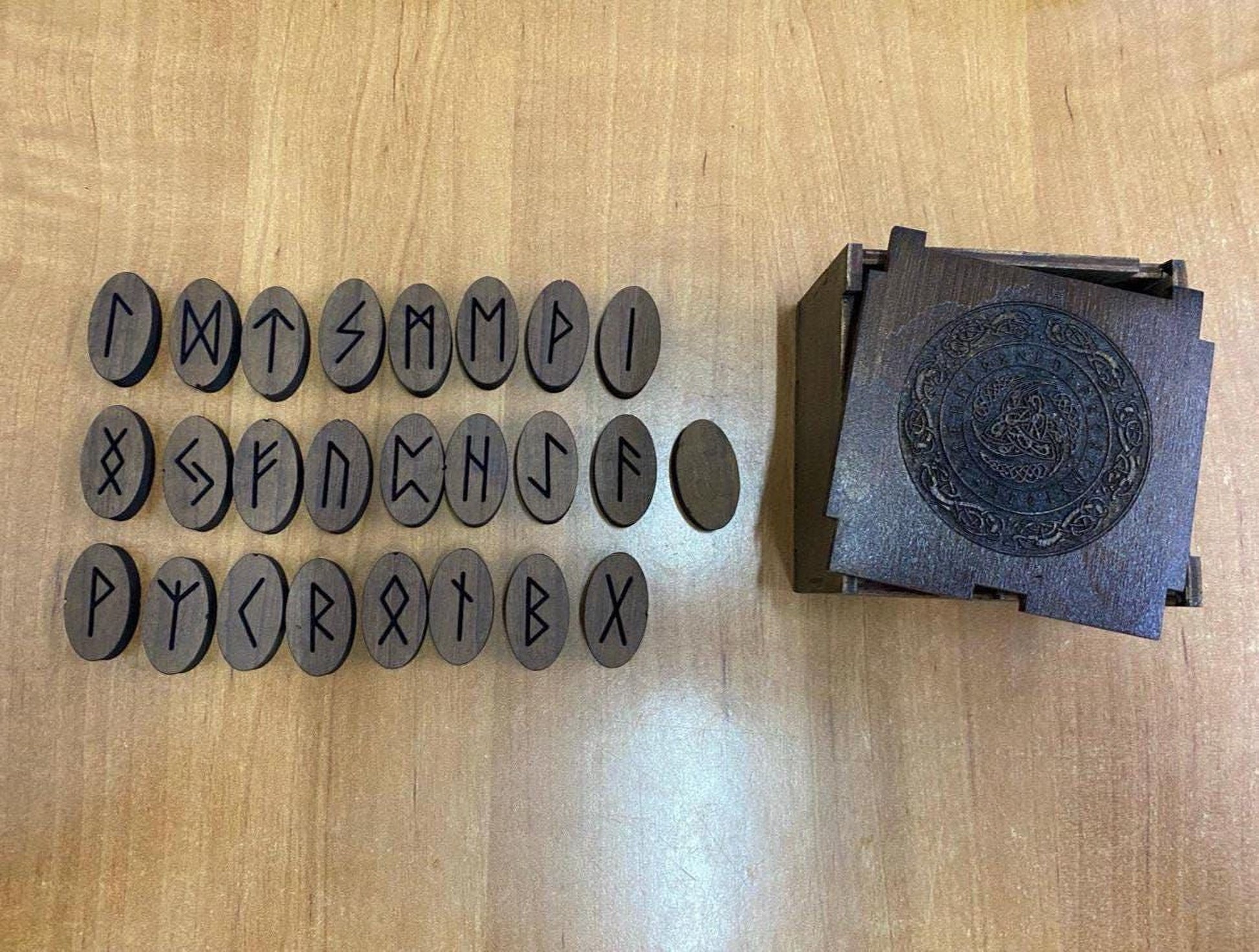 a collection of wooden objects, including a wooden box with a carved design and a row of wooden blocks with various symbols and letters carved into them.