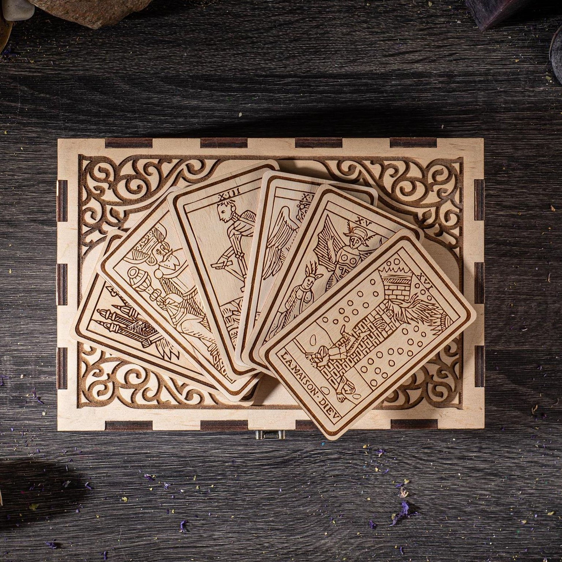 A wooden box with a decorative border, containing a set of wooden cards with intricate designs on them.