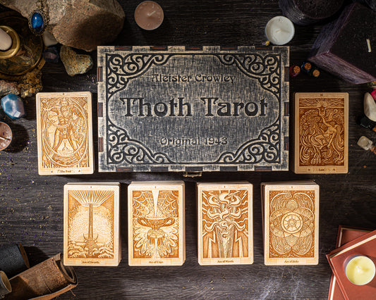 a collection of tarot cards arranged on a wooden surface, with a decorative box featuring the text "Thoth Tarot" and the number "1" prominently featured.