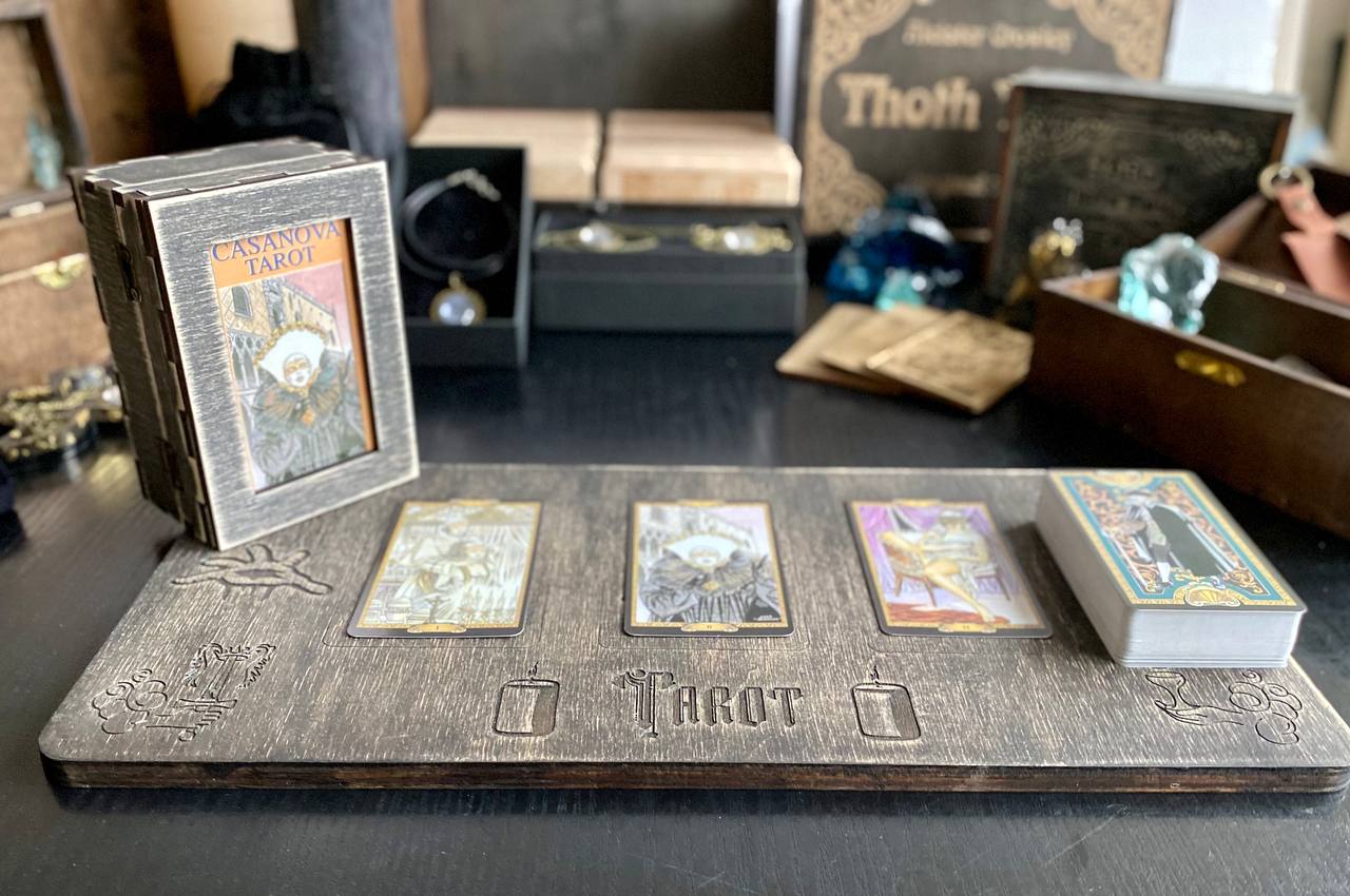 a tarot deck with three cards and a wooden tray with the word "Tarot" on it, placed on a table.