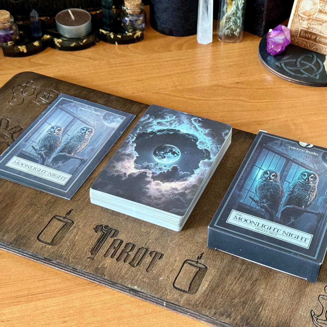 a wooden board with three tarot cards and a candle, arranged on a wooden surface.