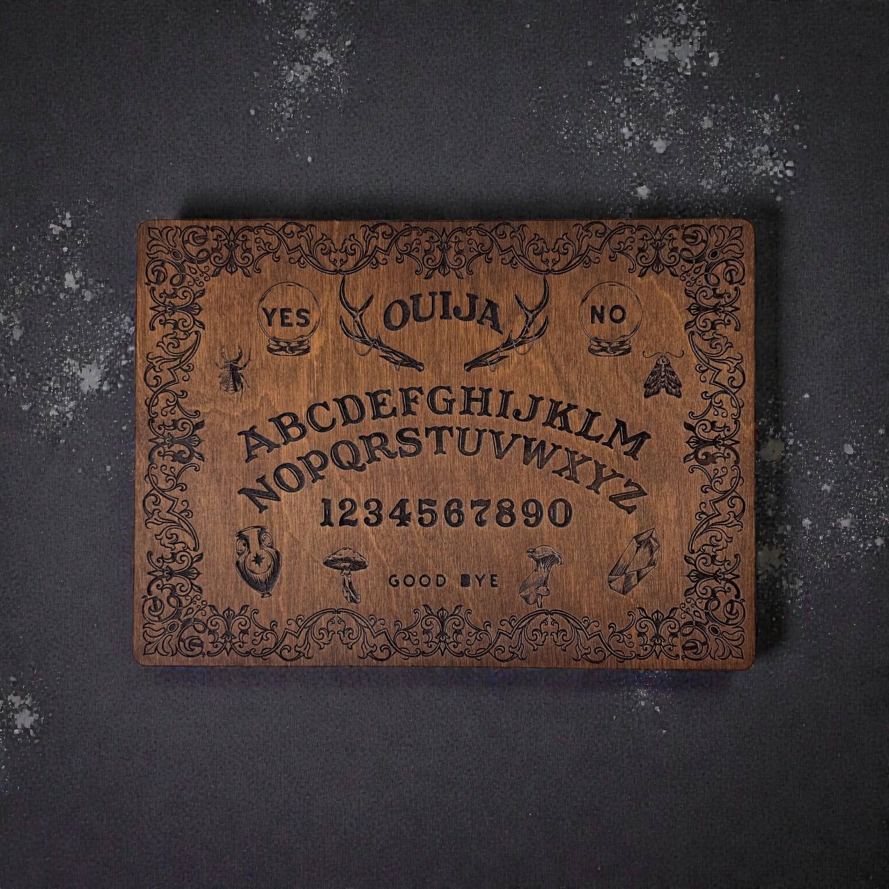 a wooden Ouija board with a decorative border and various symbols and numbers engraved on it.