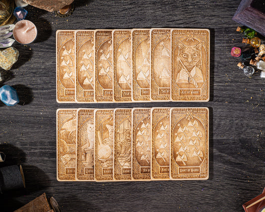 A collection of wooden tarot cards arranged on a dark wooden surface, with various objects such as crystals and gemstones scattered around them.