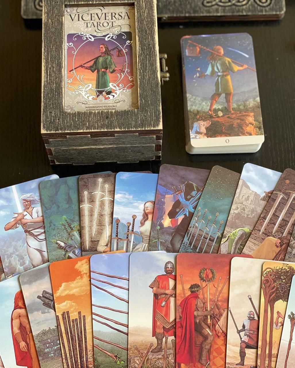 a collection of tarot cards and a wooden box, arranged on a dark surface.