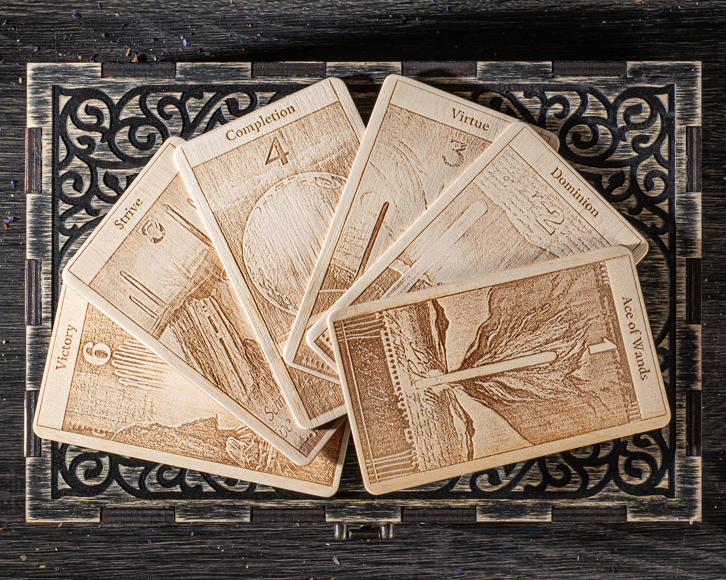 A collection of wooden tarot cards arranged in a fan-like pattern on a wooden surface.