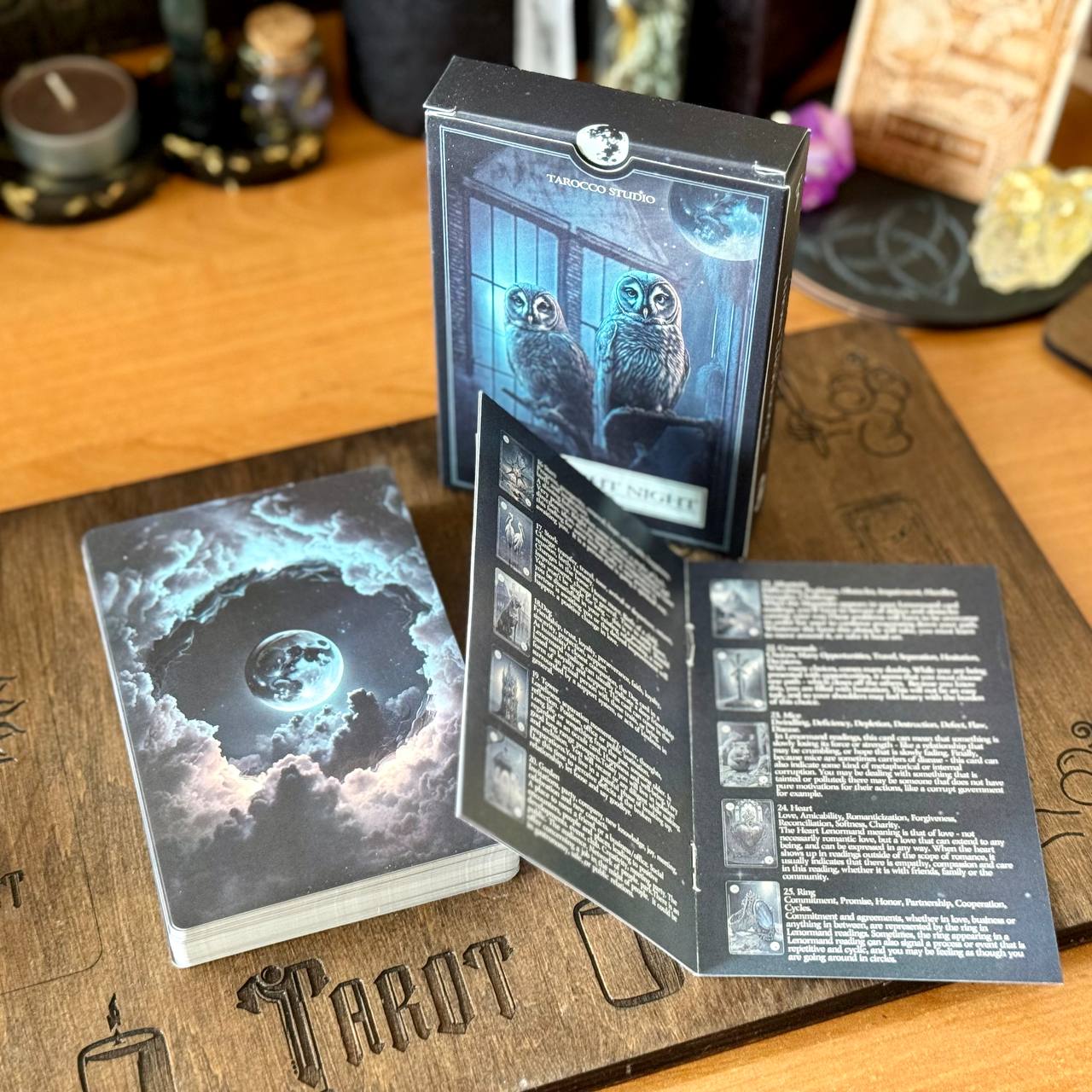 a tarot deck with a moon and clouds design, along with an open booklet containing a list of tarot card meanings.