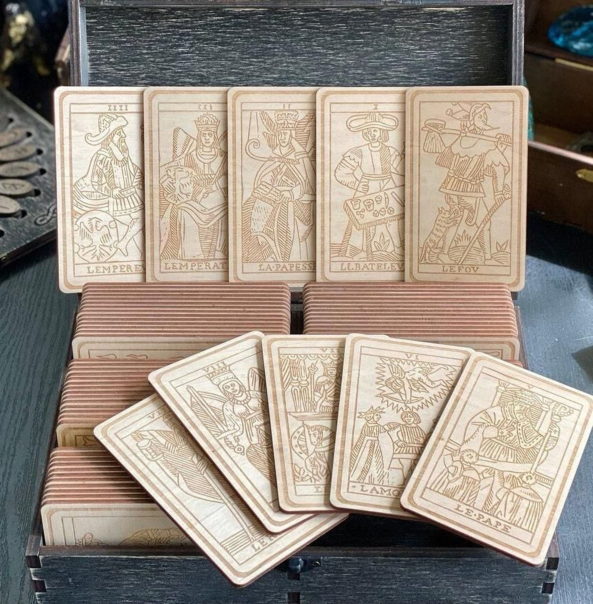 A wooden box containing a collection of wooden tarot cards, each with intricate designs and illustrations.