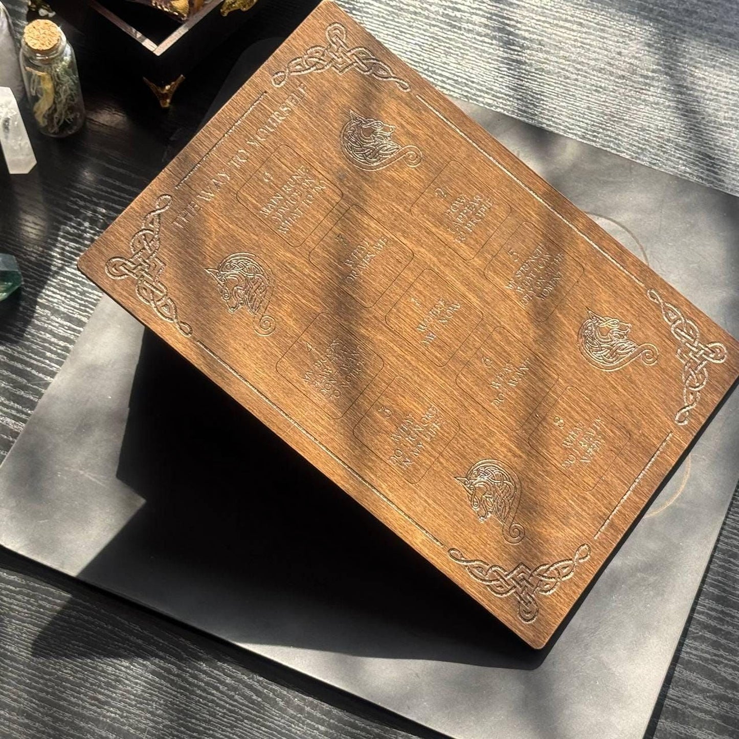 a wooden board with intricate designs and text, placed on a wooden surface.