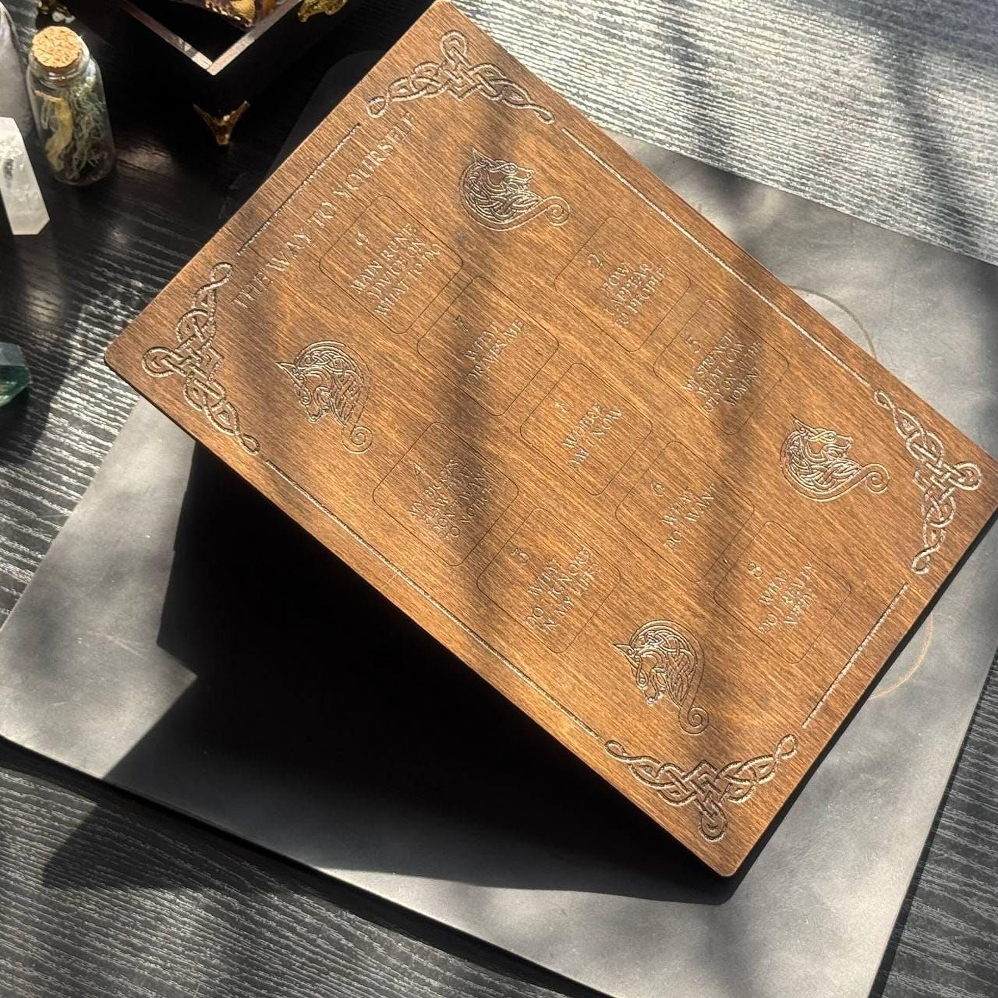a wooden board with intricate designs and text, placed on a wooden surface.
