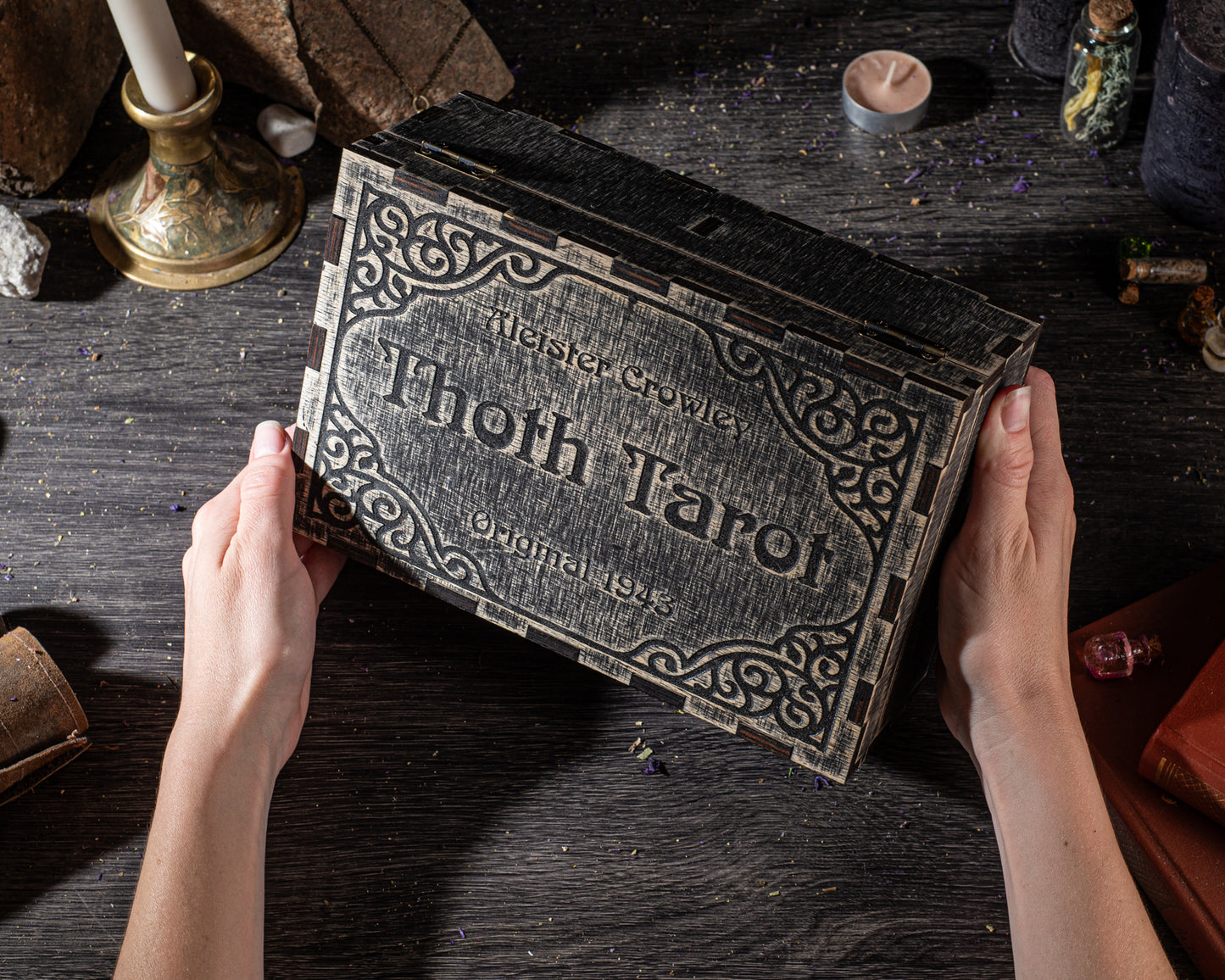A person's hands holding a large, ornate tarot card box with the name "Thoth Tarot" on it.