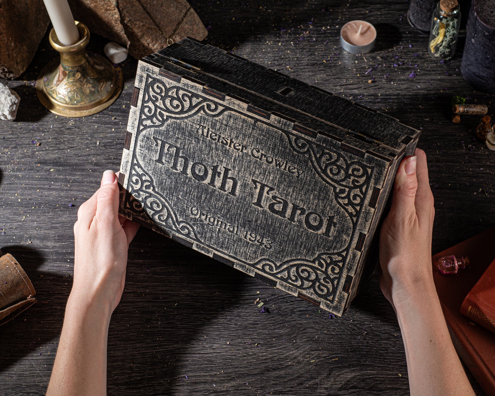 A person's hands holding a large, ornate tarot card box with the name "Thoth Tarot" on it.