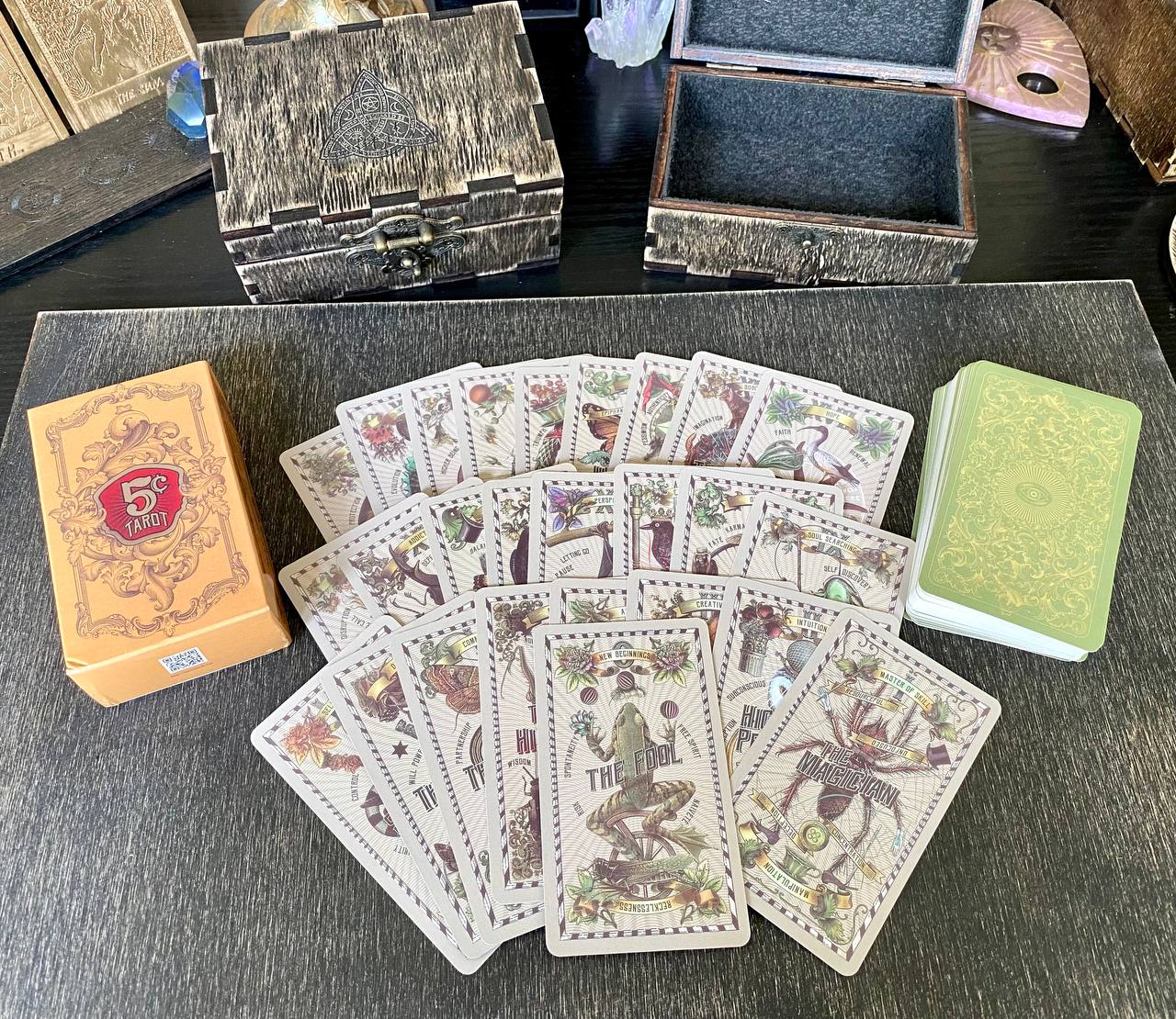 a collection of tarot cards and a wooden box on a table, with a green book and a wooden box in the background.