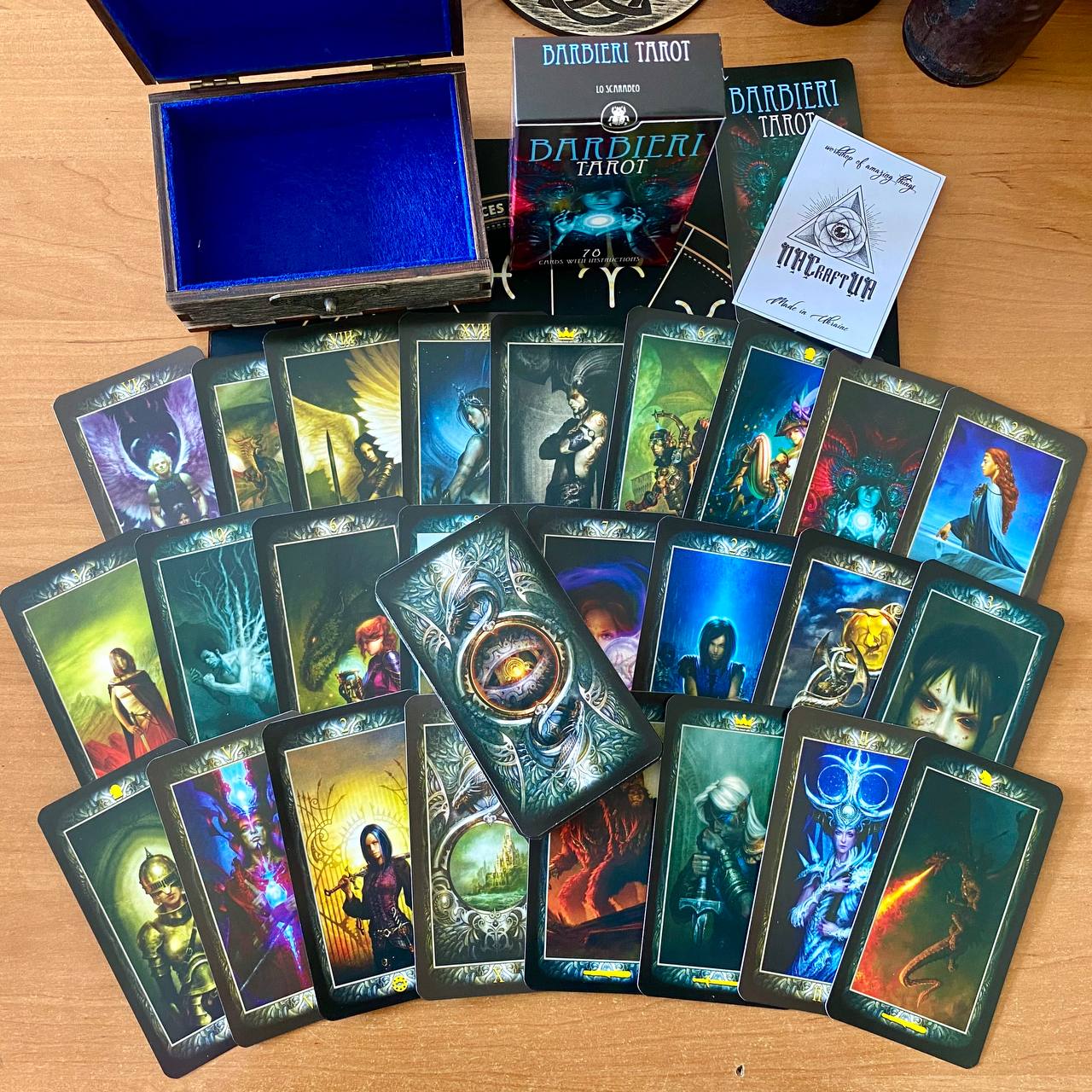 a collection of tarot cards and a wooden box, likely containing additional cards and a guidebook, arranged on a wooden surface.