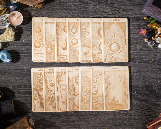 A collection of wooden tarot cards arranged on a dark wooden surface, with various objects scattered around them.