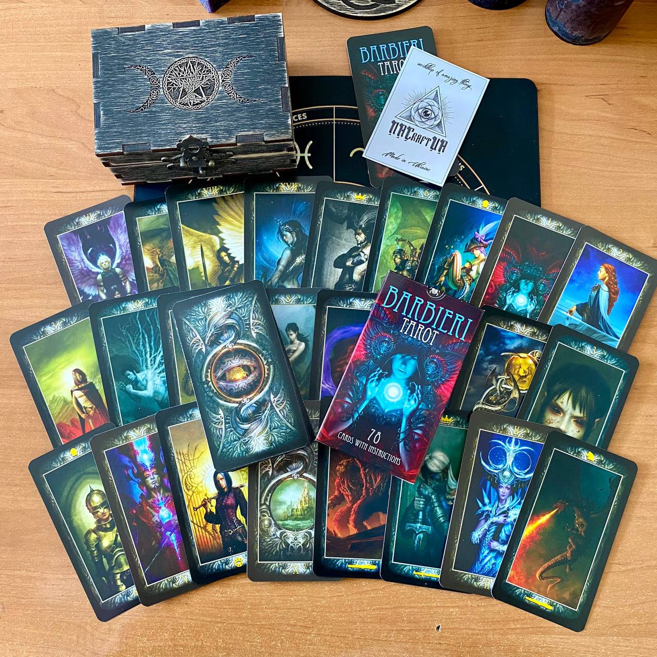 a collection of tarot cards and a wooden box, possibly a tarot kit, arranged on a wooden surface.