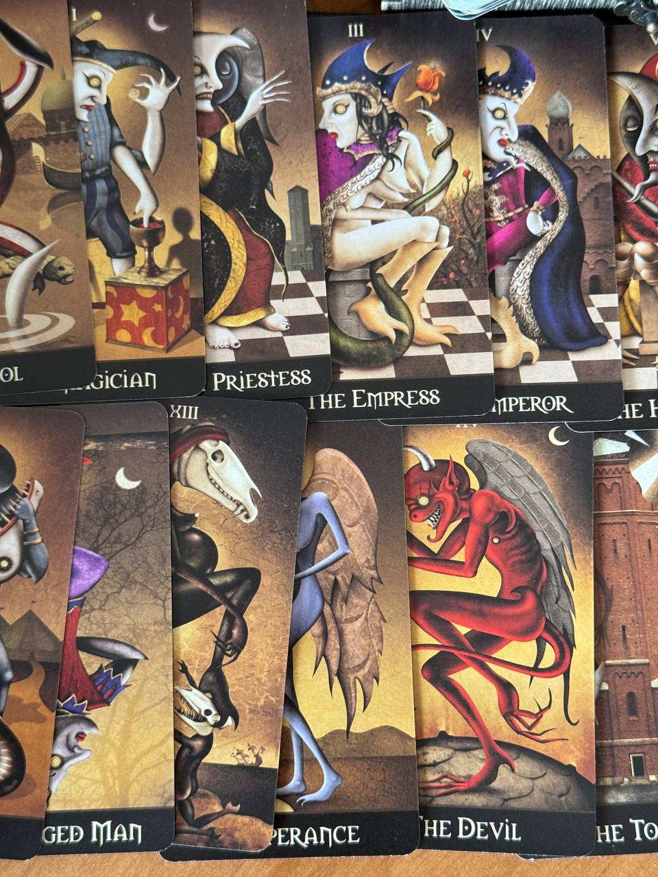 a collection of tarot cards with various fantastical and surreal illustrations, including characters such as a wizard, a priestess, a dragon, and a devil.