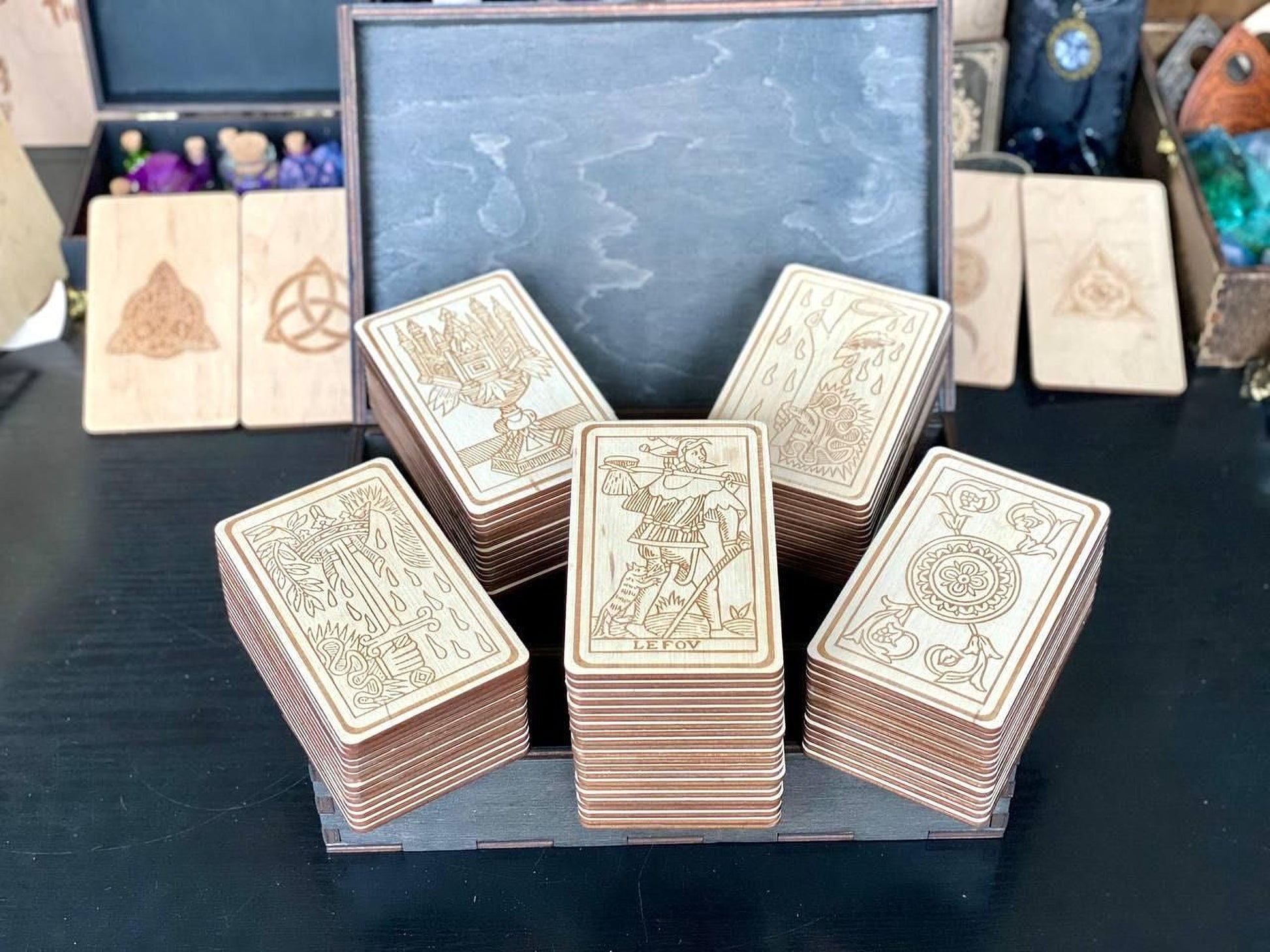 A collection of wooden tarot cards displayed in a wooden box, with various designs and symbols visible on the cards.
