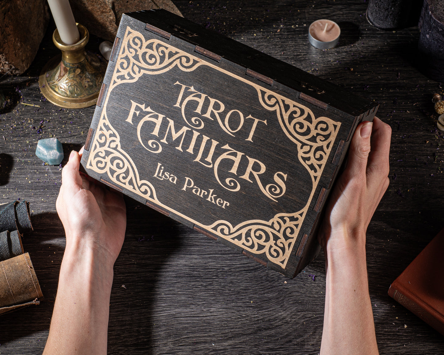 A person's hands holding a wooden box with the title "Tarot Familiars" written on it.