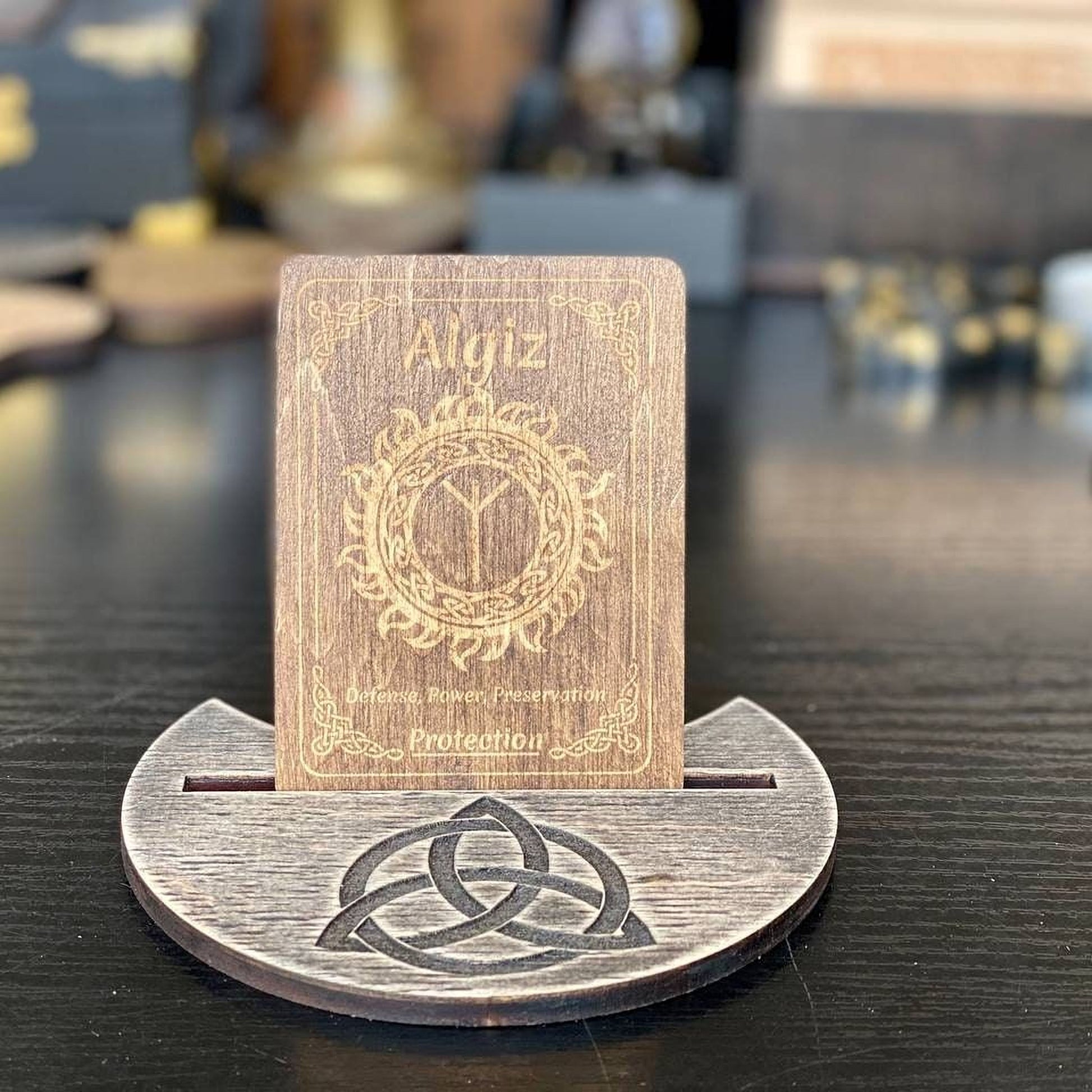 A wooden card stand displaying a wooden card with the name Aliz and a Celtic knot design.