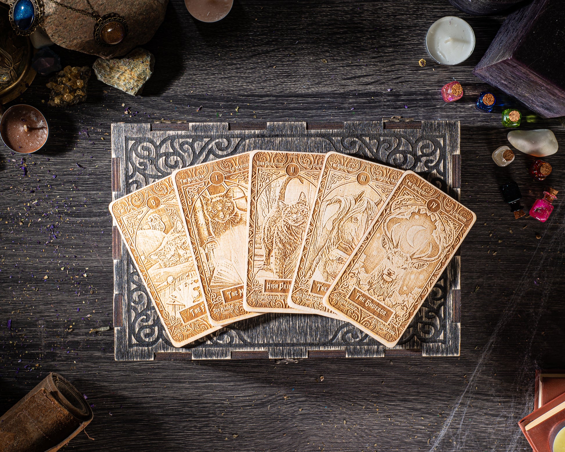 a collection of five ornate tarot cards arranged on a wooden surface, surrounded by various objects such as candles, gemstones, and other decorative items.