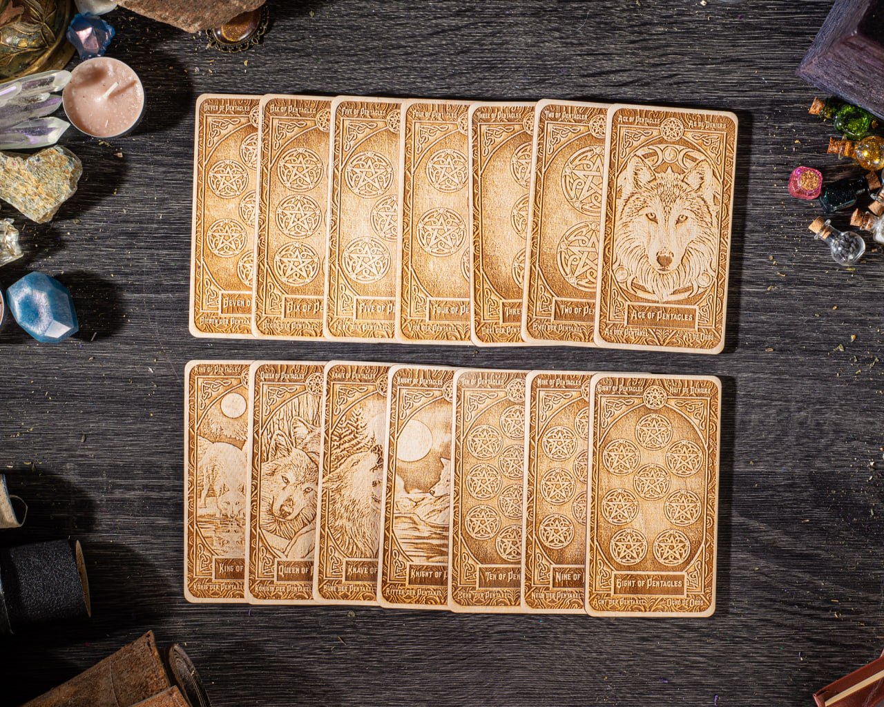A collection of wooden tarot cards arranged on a dark wooden surface, with various objects such as candles, gemstones, and other items scattered around them.
