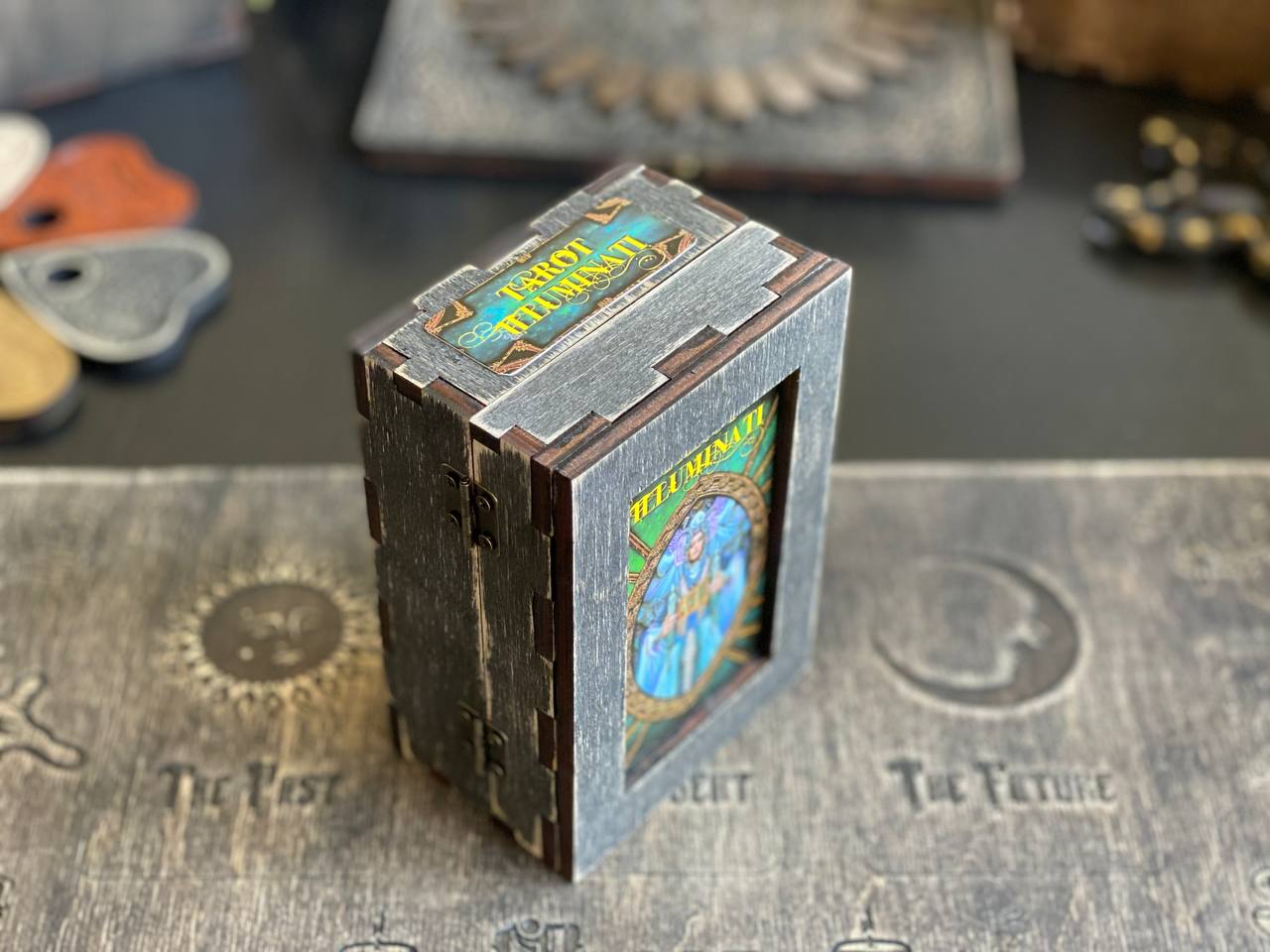 A wooden box with a colorful label, sitting on a wooden surface with various other objects in the background.
