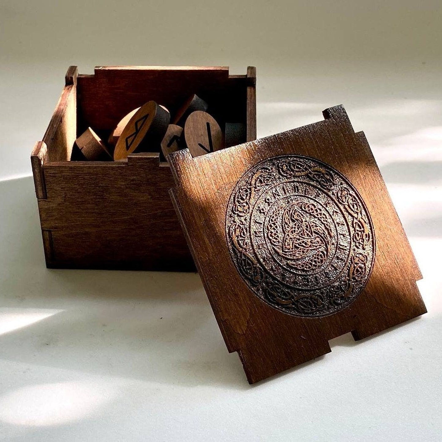 a wooden box with a lid, and inside the box, there are several wooden objects, including what appear to be wooden puzzle pieces or blocks.