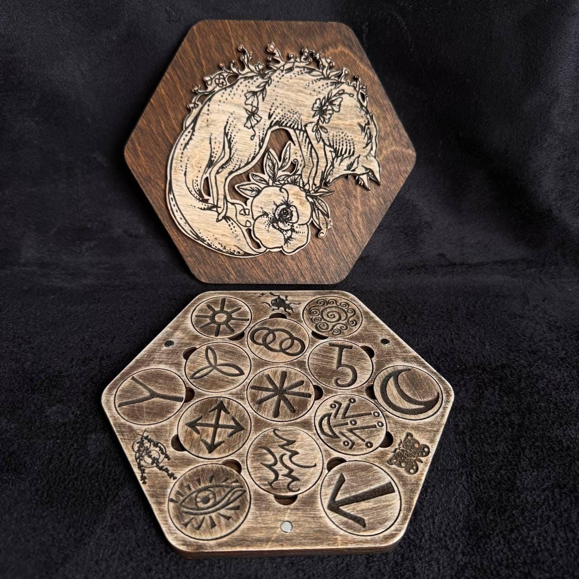 two wooden hexagonal boards with intricate designs and symbols carved into them.
