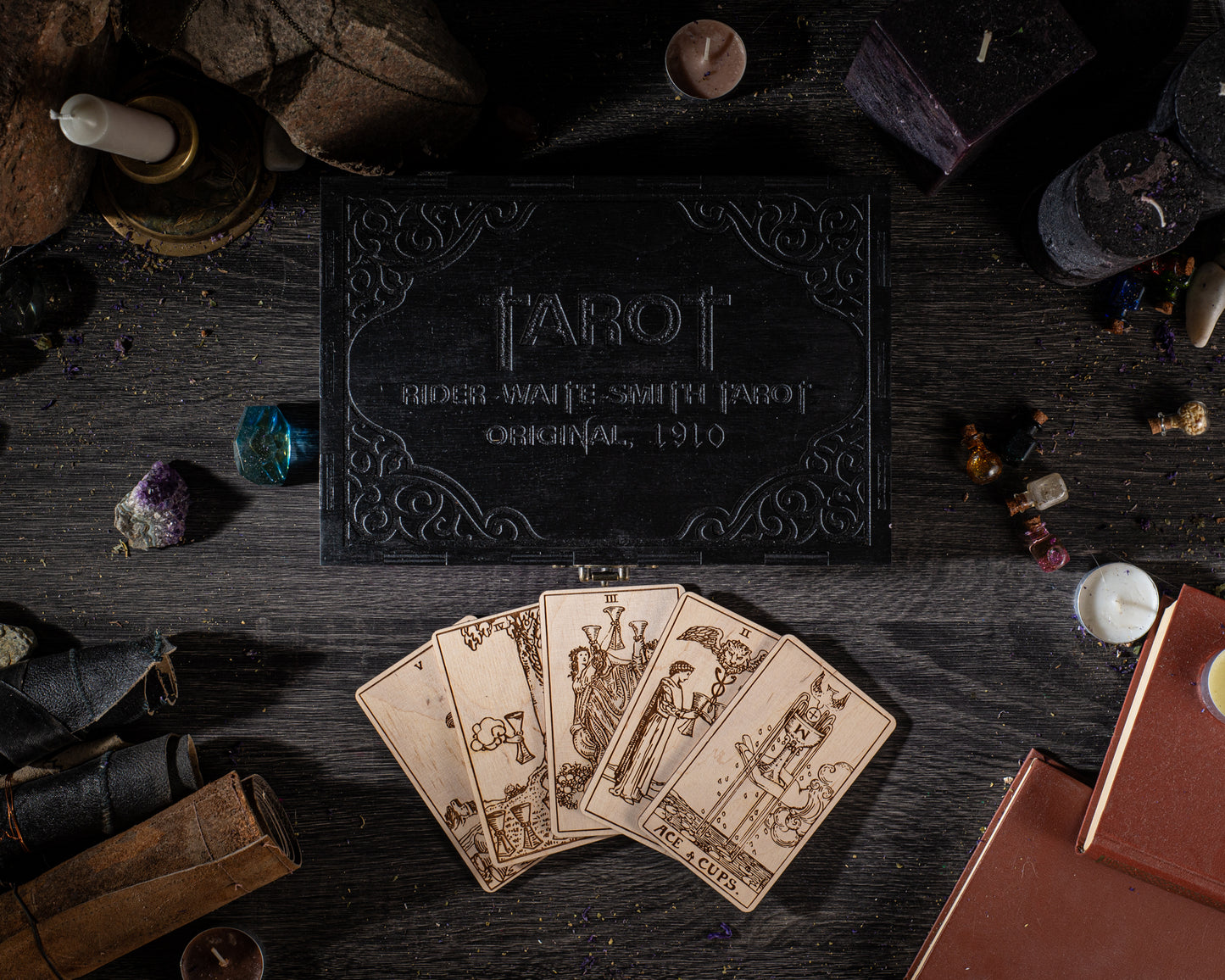 a tarot card reader's box, a deck of cards, and various mystical objects arranged on a dark wooden surface.