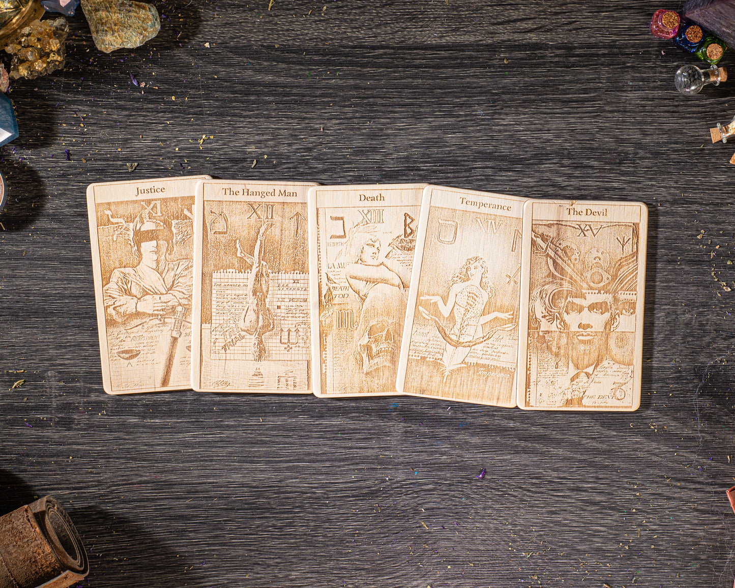 A collection of five tarot cards laid out on a wooden surface, each depicting a different scene or character.
