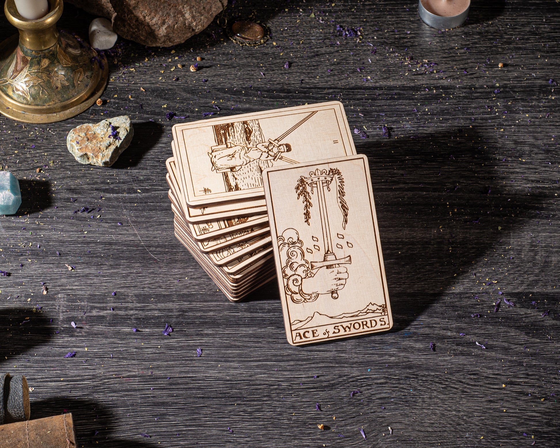 A stack of wooden cards with illustrations on them, along with various crystals and other objects on a wooden surface.