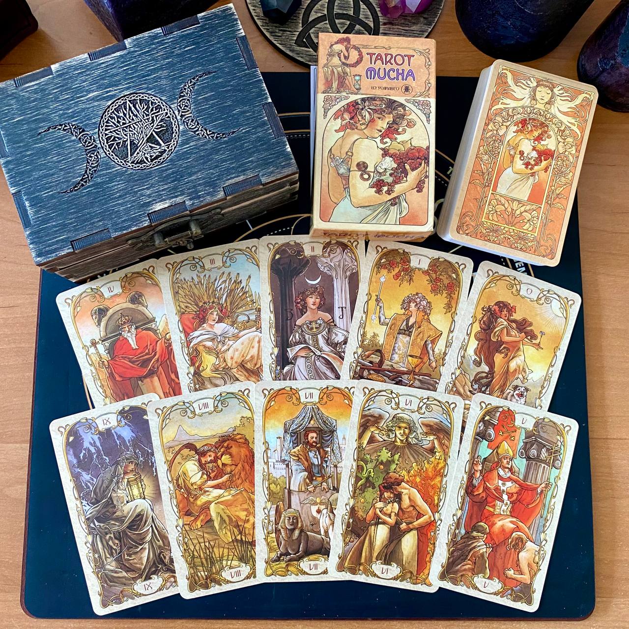a collection of tarot cards and a wooden box, likely containing additional cards or accessories, arranged on a wooden surface.