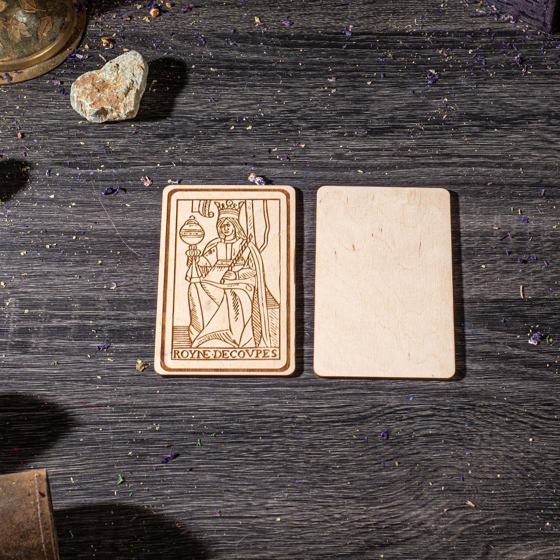 a wooden card with an embossed design, placed on a wooden surface with scattered rocks and other objects.