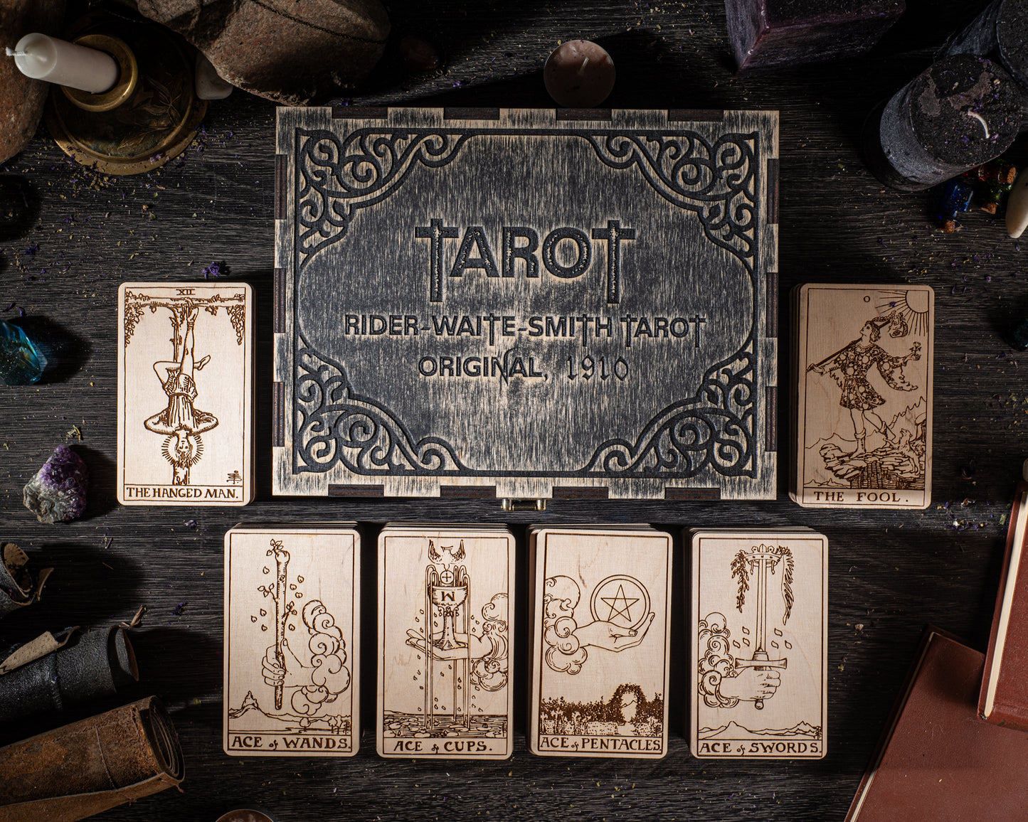 a collection of tarot cards and a wooden box with the text "RIDER-WAITE SMITH TAROT ORIGINAL 1910" on it, all arranged on a dark wooden surface.