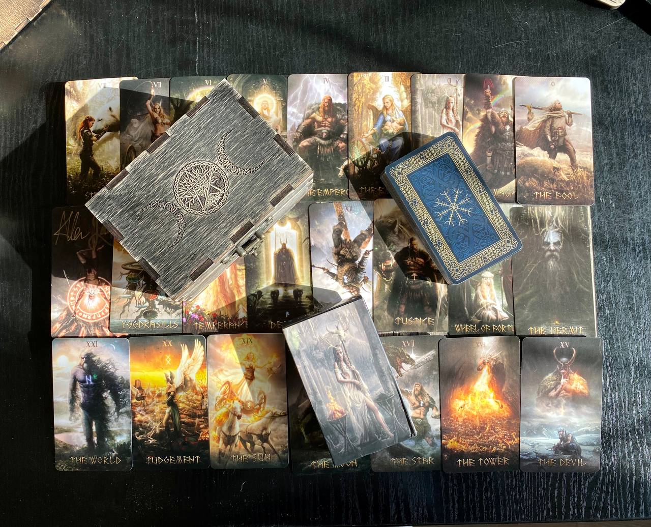 a collection of tarot cards and a wooden box, arranged on a dark surface.